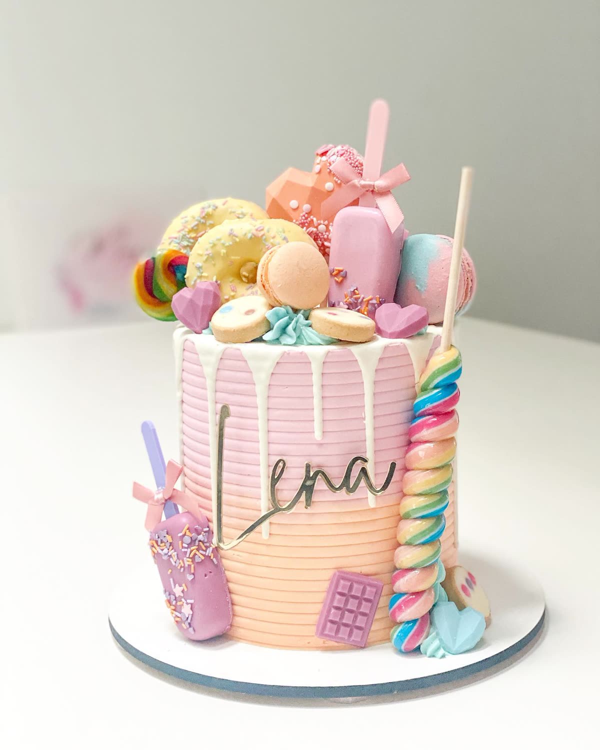 Pink drip cake with macarons, candy and a lollipop — Ming's Cake Boutique
